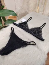 Conjunto de lencería negro de encaje, compuesto por un bralette con breteles regulables y una tanga regulable con corte media less y entrepierna de algodón.