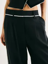 Pantalón negro de corte recto y tiro alto, con bolsillos laterales y detalle de ribete blanco en cintura y laterales.