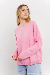 Remera rosa de algodón con mangas largas y ruedo con puntilla calada.