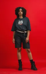 Remera de algodón premium color carbón, corte oversize, con cuello redondo y manga corta. Presenta un estampado frontal con calaveras en estilo caricaturesco, una de ellas con sombrero de copa, rodeadas de humo o nubes, y el texto "CHILLED THE BONE".