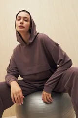 Canguro marrón con capucha, corte amplio y detalle de recorte frontal.