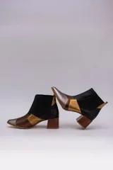 Botinetas de cuero con diseño patchwork en negro, dorado, plateado y marrón. Tienen elásticos laterales, taco cuadrado de madera y puntera fina.