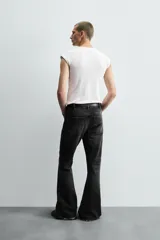 Pantalón de jean celeste, de tiro medio, corte ajustado en la parte superior y acampanado desde la rodilla. Tiene cinco bolsillos, efecto lavado y bajo irregular.
