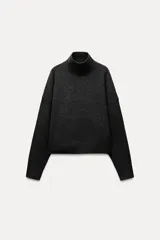 Jersey de punto color gris oscuro, de cuello alto y manga larga con terminaciones en rib.