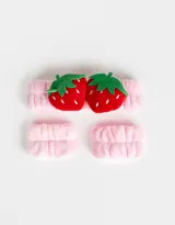 Set de accesorios para el pelo color rosa, compuesto por una vincha con apliques de frutillas y dos muñequeras.