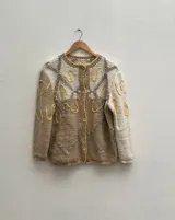 Cárdigan tejido a mano en una mezcla de lana merino y seda natural, con una silueta holgada, manga caída y escote clásico. Incorpora bordados artesanales y botones.