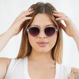 Lentes de sol negros con forma ovalada y detalles dorados en el marco.