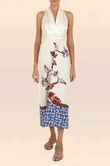 Vestido largo color crema con estampado de flores y hojas en tonos marrón y celeste. Tiene escote halter con tiras que se atan en la nuca y falda con vuelo.