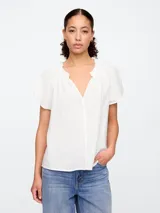 Blusa blanca de manga corta con escote en V y detalle de volados en el cuello.