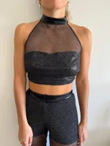 Top corto de malla negra con detalles en charol, diseño ajustado de halter.