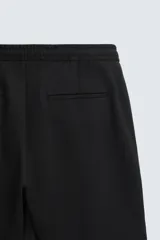Bermuda color crudo de corte recto, con cintura elástica ajustable con cordón, pliegues frontales, bolsillos laterales y bolsillos traseros de vivo.