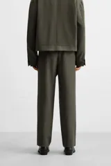 Pantalón largo color verde oscuro, de corte recto y tiro medio. Confeccionado en tejido con viscosa, con cintura elástica, bolsillos laterales y trasero de vivo. Cierre frontal con cremallera y botón.