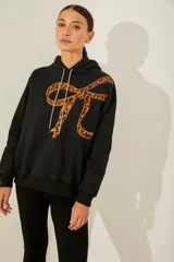 Buzo negro de frisa oversize con capucha y bordado de moño print animal en gamuza en el delantero.