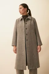 Tapado largo con cuello solapa y corte recto, color gris claro. Tiene cierre frontal con botones ocultos, tajos laterales y bolsillos escondidos en el corte lateral. Está forrado y confeccionado en lana fina sin teñir, diseñada exclusivamente por Don Baez. Hecho 100% en Uruguay.