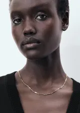 Chaleco negro de punto fino, sin mangas, con tirantes anchos, diseño recto, cuello de pico y cierre delantero con botones.