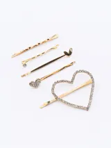 Set de cinco hebillas doradas para el pelo, con diferentes diseños: una con forma de corazón con strass, una con forma de corazón liso, una con strass, una lisa y una retorcida.