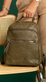 Mochila color caramelo de símil cuero, con dos bolsillos frontales con cierre y bolsillos laterales abiertos. Interior forrado con dos bolsillos con cierre y uno abierto. Tiene asa de mano y correas regulables.