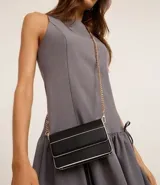 Cartera transversal pequeña de poliuretano negro con detalles en blanco y asa de cadena dorada.