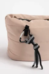 Necesser de poliéster color beige con diseño capitoneado y cierre superior con cremallera negra.