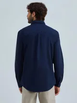 Camisa de vestir azul marino, de corte clásico, con cuello abotonado, manga larga y bolsillo en el pecho.