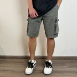 Bermuda cargo color gris con efecto lavado, de corte recto y largo hasta la rodilla. Cuenta con bolsillos laterales tipo cargo con solapa y botón, bolsillos delanteros y traseros.