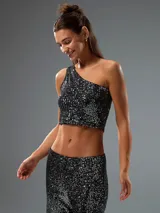Top corto negro de un solo hombro, con lentejuelas plateadas.