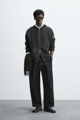 Pantalón negro de corte ancho, con pinzas en la cintura, bolsillos laterales y traseros de ojal.