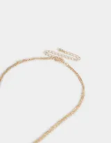 Collar corto dorado multicadena con dije de moño y mini dijes con strass.