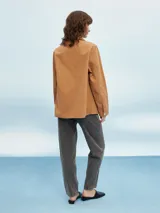 Sobrecamisa color beige, de corte recto, con cuello camisero, cierre frontal con botones a presión, mangas largas con puños abotonados, dos bolsillos de parche en el pecho y bajo recto.