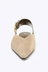 Zapato plano destalonado color beige, de serraje, con punta fina y tira trasera con hebilla metálica.