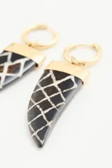 Aros colgantes con forma de cuerno, con base dorada y colgante negro con diseño geométrico blanco.