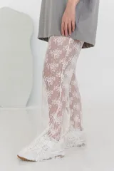 Pantalón acampanado de encaje blanco con diseño floral.
