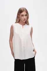 Blusa viscosa color negro, corte evasé, sin mangas, con cuello a la base y botón en la parte superior.