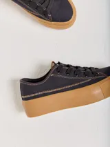 Championes bajos de lona color crema con pespuntes rojos y suela de goma color caramelo.