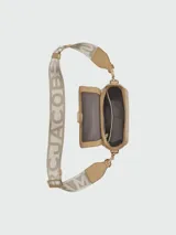 Bandolera de cuero color beige con correa ancha de tela con el logo de la marca en color crudo.