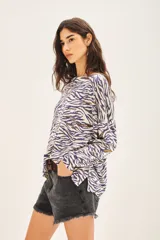 Sweater de tejido animal print con base color crema y rayas color azul y marrón. Tiene tajos laterales y lentejuelas bordadas.