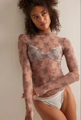 Top de manga larga confeccionado en tejido de malla semi-transparente con diseño bicolor y estampado floral abstracto. Presenta cuello redondo alto y un calce ajustado al cuerpo.