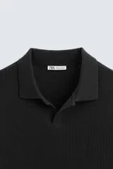 Polo azul marino de punto con textura acanalada vertical, corte regular fit, cuello solapa con abertura frontal y mangas cortas.