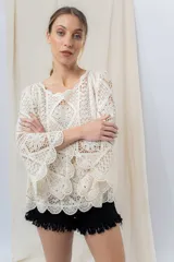 Blusa tejida calada color crudo, con diseño geométrico y motivos florales, escote redondeado y mangas 3/4 con leve vuelo.