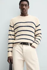 Sweater de punto color crema con rayas horizontales azul marino, cuello redondo y manga larga.