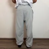 Pantalón sastrero color beige, de corte baggy, con pliegues en la cintura y bolsillos laterales.