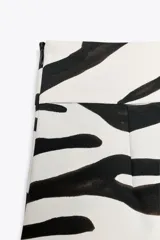 Pantalón de tiro medio con estampado animal cebra, corte palazzo y cierre lateral con cremallera oculta.
