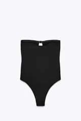 Bañador enterizo negro tipo bandeau, con escote recto, hombros descubiertos, copas extraíbles, forro interior y detalle de aberturas en el pecho con aplicación de anillas metálicas doradas.