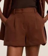 Short de vestir color marrón con cintura alta, trabillas, pliegues delanteros y bolsillos laterales.