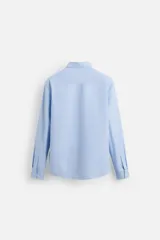 Camisa celeste de corte slim fit, confeccionada en tejido de algodón. Tiene cuello italiano, mangas largas con puños abotonados y cierre frontal con botones.