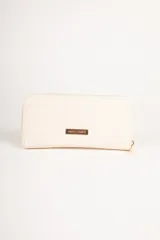 Billetera color beige con cierre de cremallera y apliques de tachas doradas en forma de corazón.