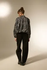 Campera estilo bomber de manga larga, con cuello mao y cierre frontal. Confeccionada en tejido de poliéster con estampado de piel de serpiente en tonos grises y negros.