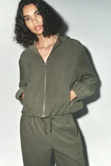 Cazadora bomber verde militar con capucha, cierre frontal con cremallera y bolsillos delanteros.