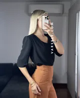 Blusa negra de crepé de lino con escote en V, mangas 3/4 con hombreras y detalle fruncido en los hombros. Se ata en la espalda con tiritas.