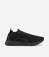 Championes negros de tela con suela blanca, estilo slip-on.